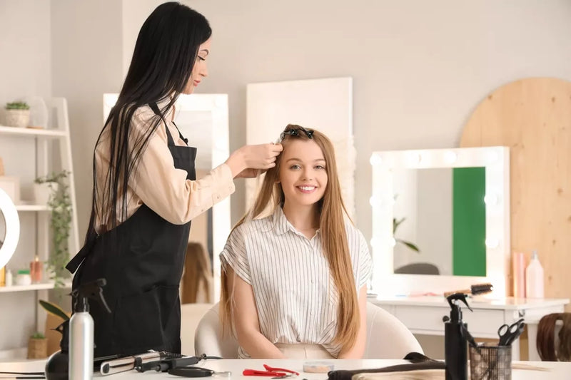 A girl at the salon gets long, blonde hair extensions.