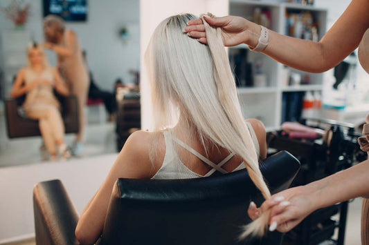 A hairdresser matching hair extensions to a client’s natural hair.