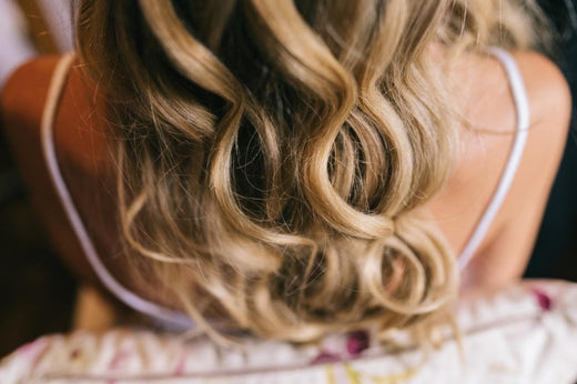  A close-up photo of a woman wearing a wavy blonde balayage wig.