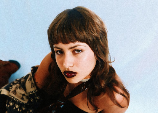 Image of a girl looking into the camera with dark lipstick and a full fringe.