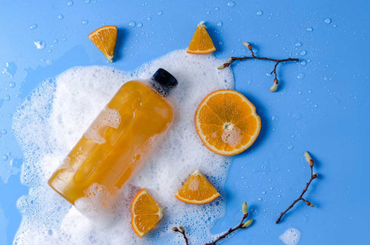 Orange shampoo with orange slices on a bubbly light blue background 