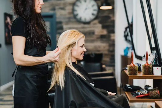 A middle aged blonde woman gets a salon haircut.