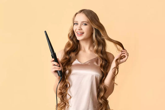 A girl uses a curling iron to curl her blonde hair extensions.