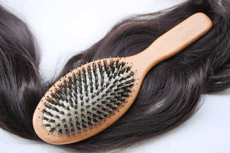 A boar bristle brush sits on top of long, dark hair.