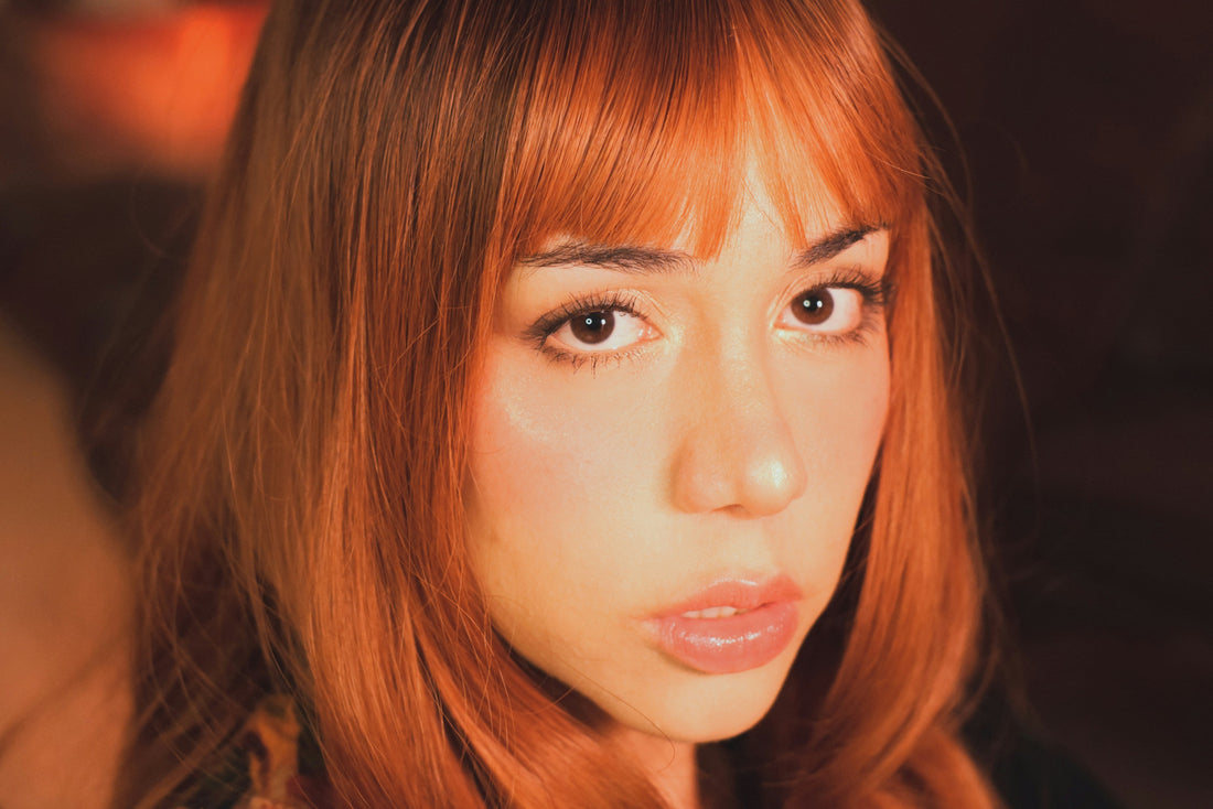  Woman with red hair and bangs looking at camera.