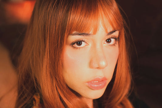  Woman with red hair and bangs looking at camera.