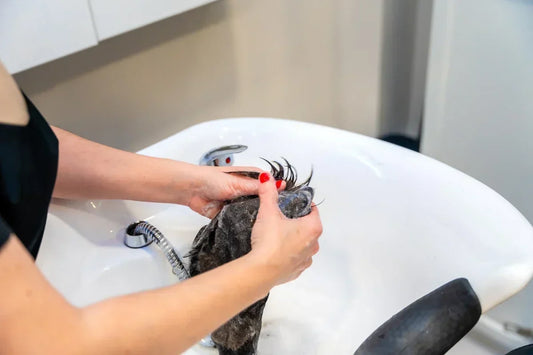 A woman cleans and conditions a wig.