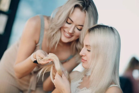 A stylist and client look at a hair extension weft together.