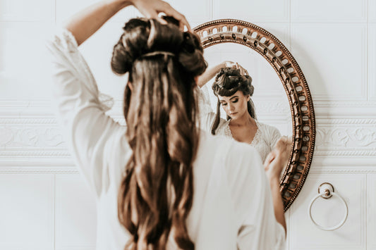 Woman combing through long brown hair styled in waves.