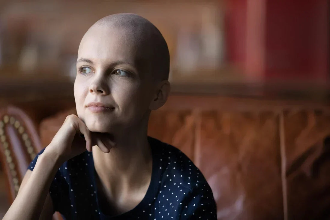 A woman with hair loss looks pensively off to the side.