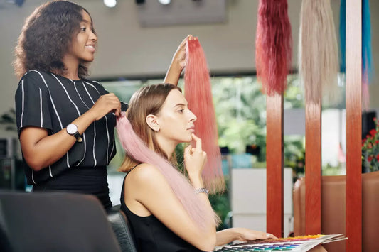A woman at a salon considers different types of hair extensions.