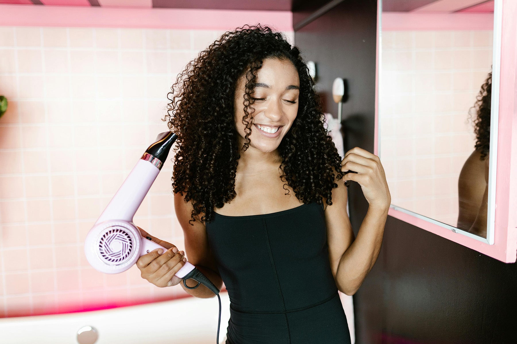 Picture of a hairdryer being held against a pink background