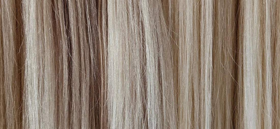 A selection of blonde human hair extensions in a row, showing the range of colors.