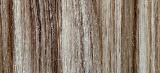 A selection of blonde human hair extensions in a row, showing the range of colors.