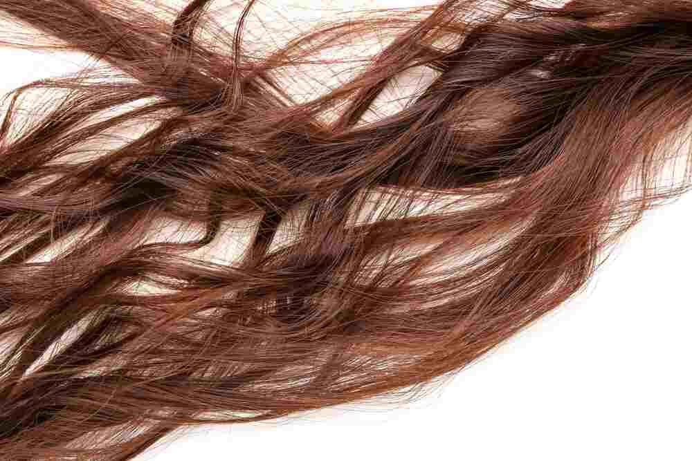 A tangled auburn hair extension against a white background