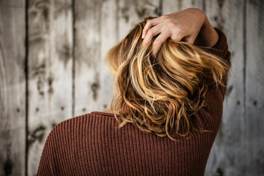 Woman running her fingers through short blonde hair, symbolizing early signs of thinning hair and exploring natural hair loss solutions.