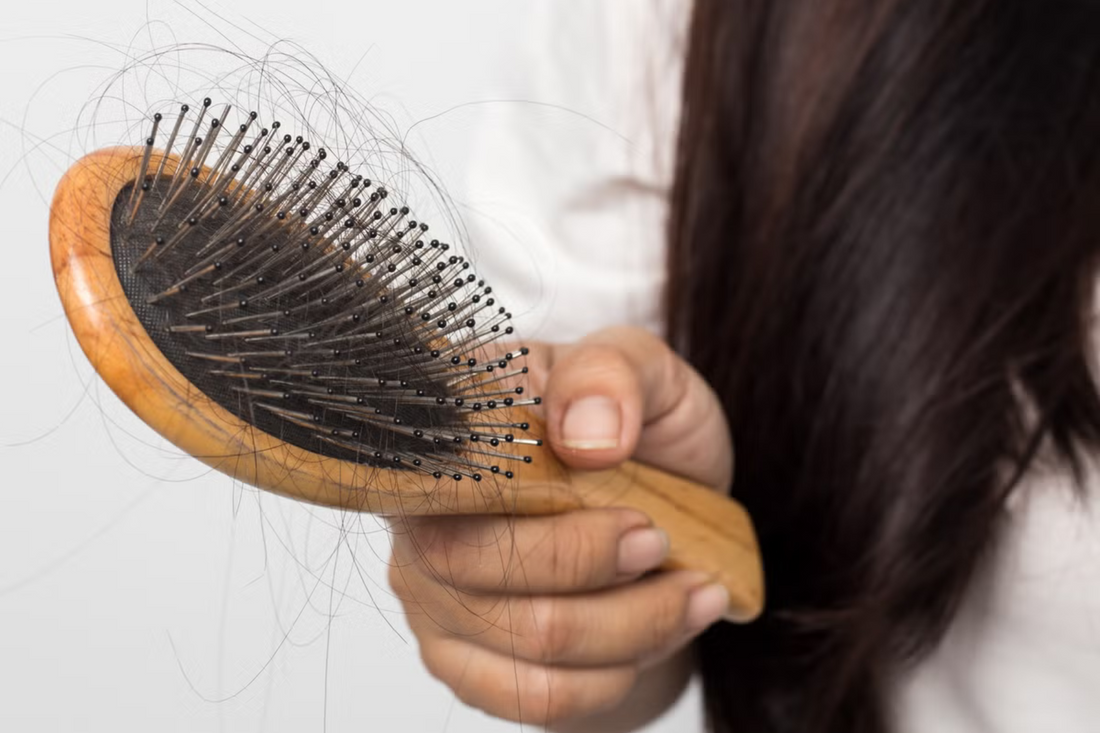 Image of a lady brushing her hair suffering from postpartum hair loss. Taken from Getty Images