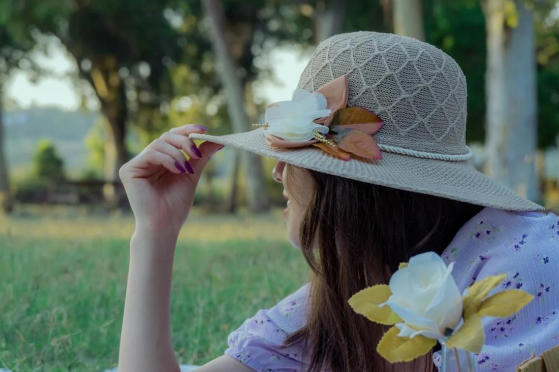 (Image of a lady sitting on the grass wearing a hat with her hair down. Taken from Pexels)