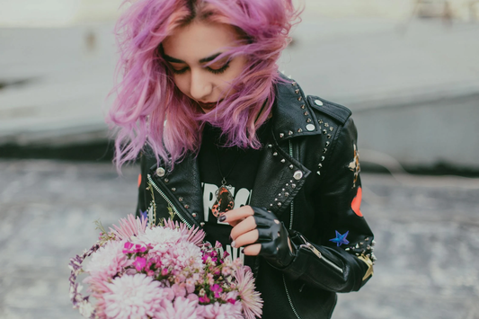 A young woman wearing a studded leather jacket with multi-tonal pink hair.