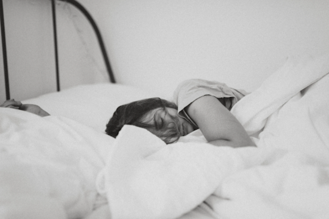 Image of a girl sleeping in bed with white bed linen. Taken from Pexels