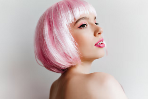 Profile view of a woman with a pink bob haircut and matching pink lipstick, standing against a white background. Source: Freepik