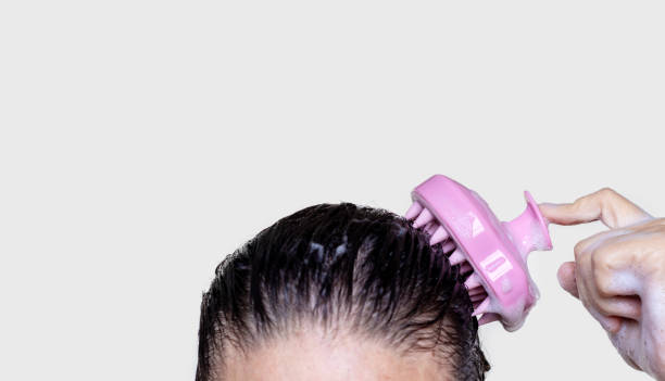 Photo of woman using scalp massager to shampoo hair