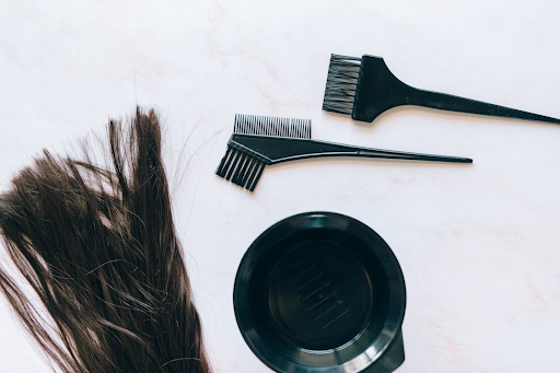A flat lay of some hair extensions positioned next to some combs and hair dye.