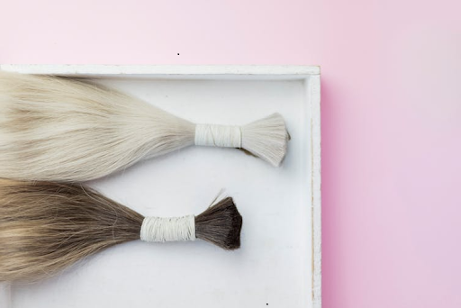 A pair of brunette and blonde hair extension bundles flat lay on a tray.