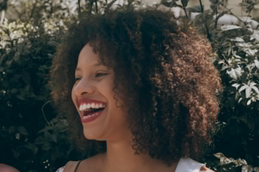 Image of a girl with curly brown hair smiling. Taken from Pexels