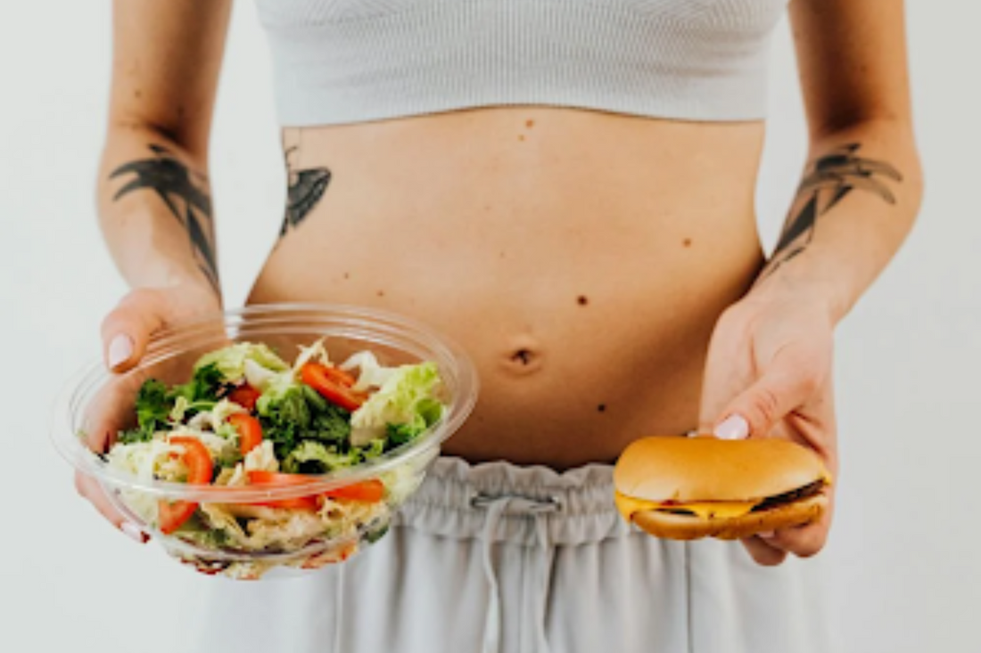 Image of a lady holding a salad and a burger. Taken from Pexels