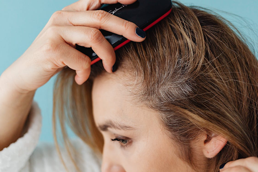 A close-up of a woman brushing her hair close to her scalp.